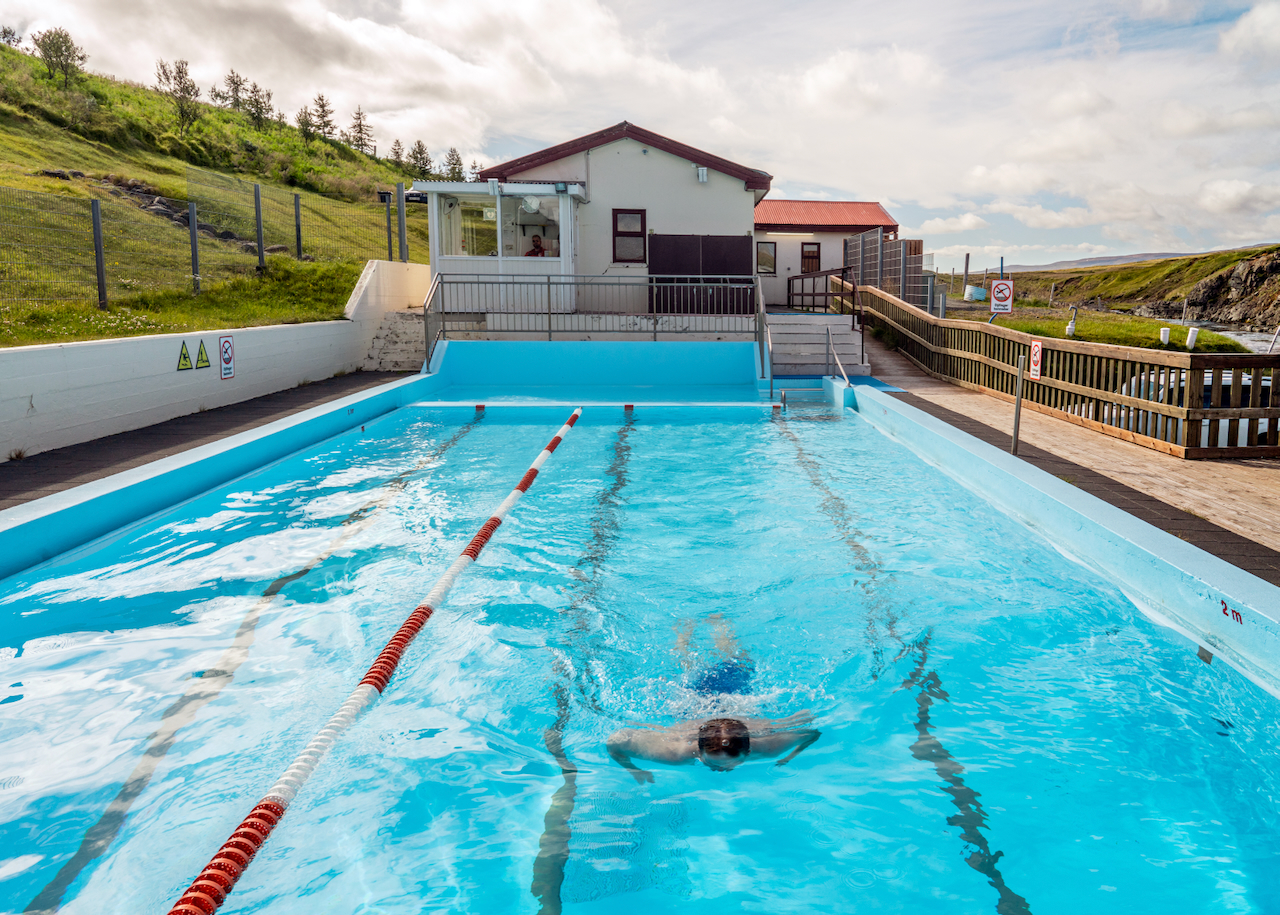 A man swimming in a small remote swimming pool, Selárdalslaug in Vopnafjörður