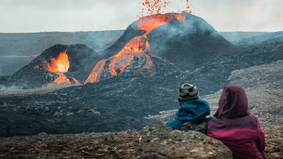 Two people watching two eruptive craters up close