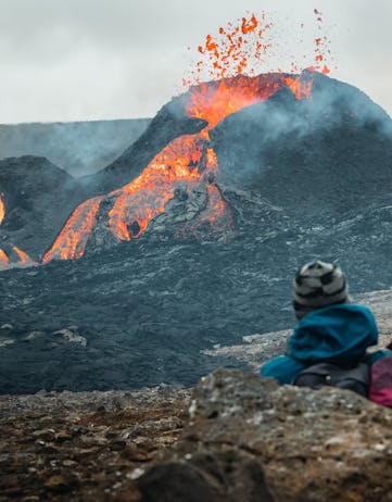 A man watching an erupting volcanic crater up close