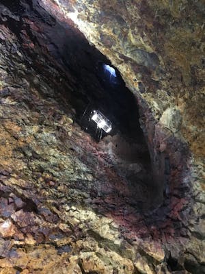 A window-elevator going into a volcanic crater with colorful rocks of yellow, black and red