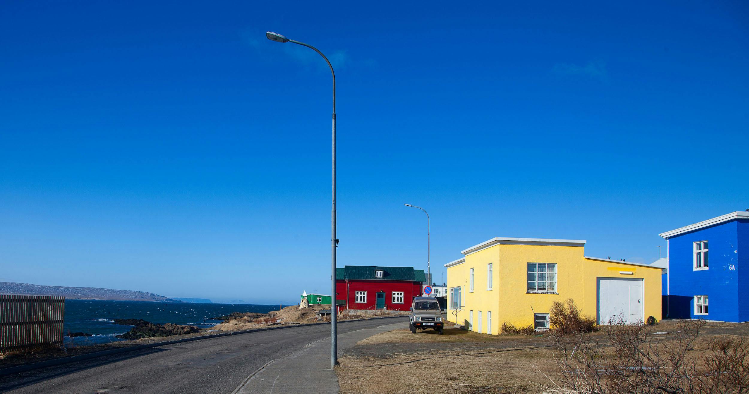 Red, yellow and blue house in a street in Hvammstangi