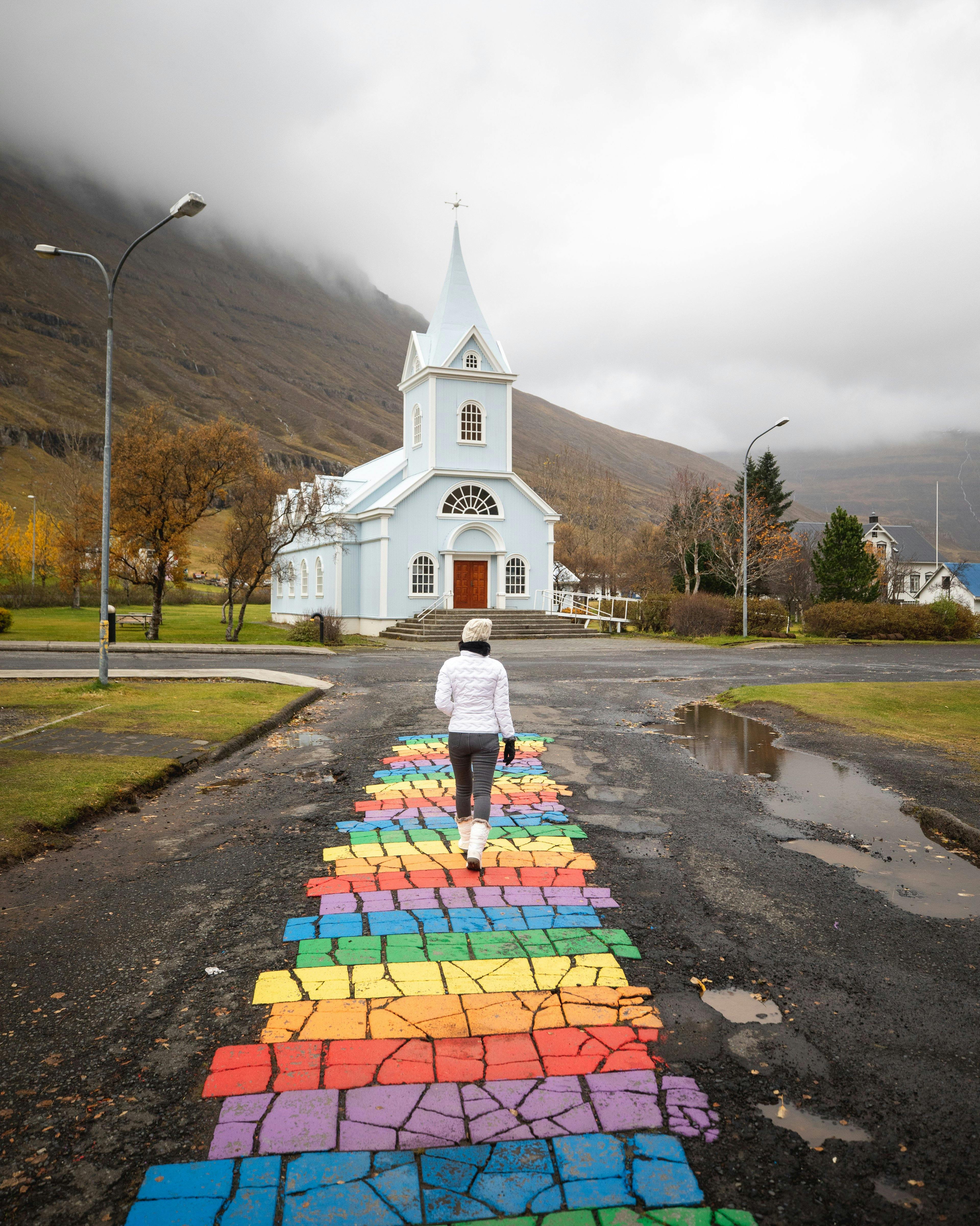 Rainbow street leading up to the white church of Seyðisfjörður, East Iceland
