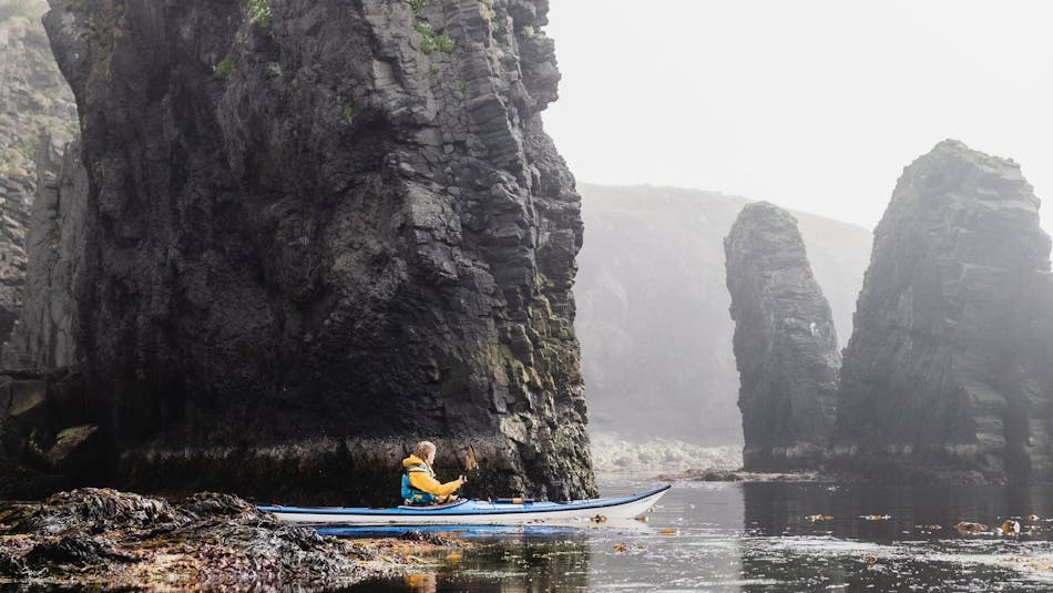 a woman driving with a kayak between rock formations in Iceland's westfjords