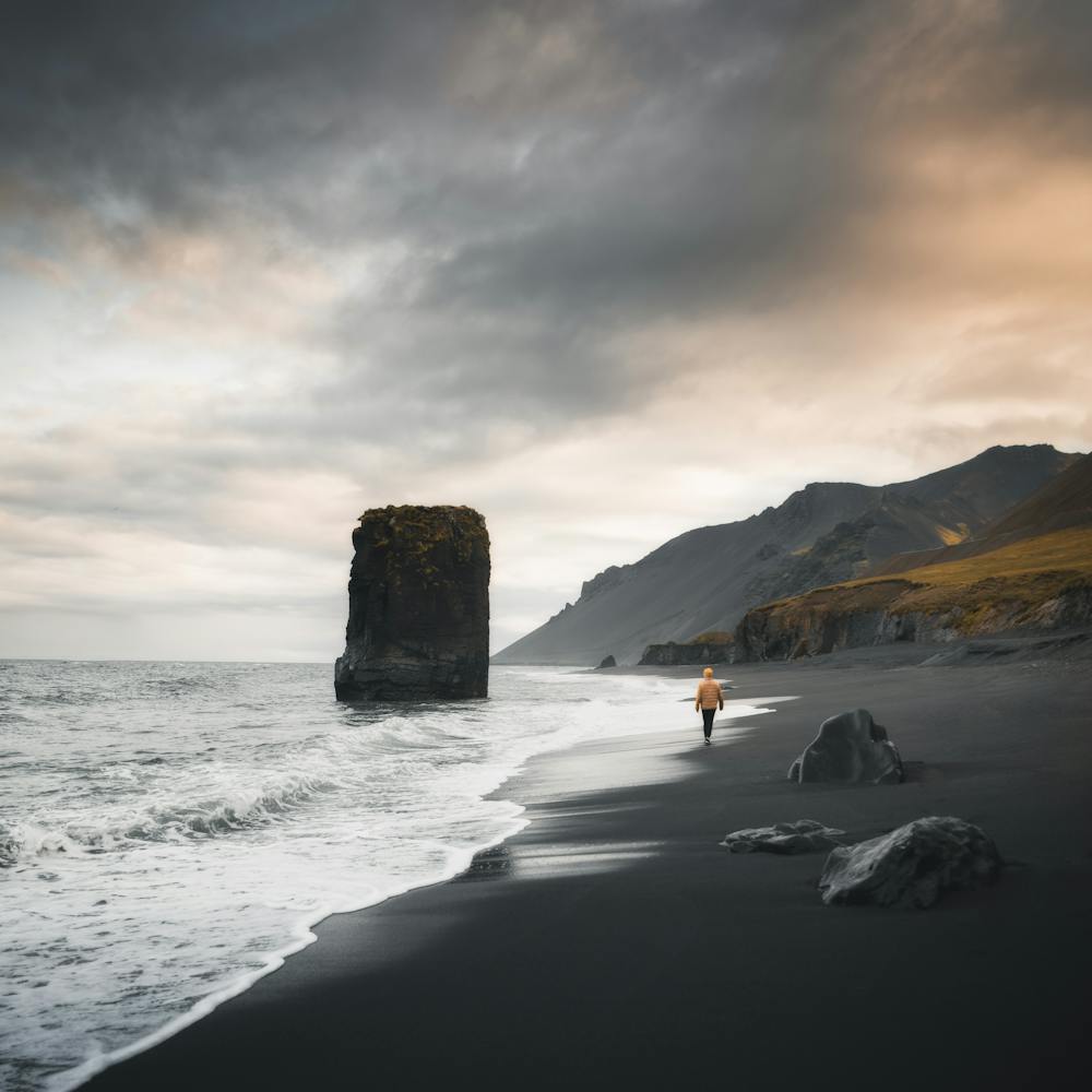 Person walking on a black sand beach