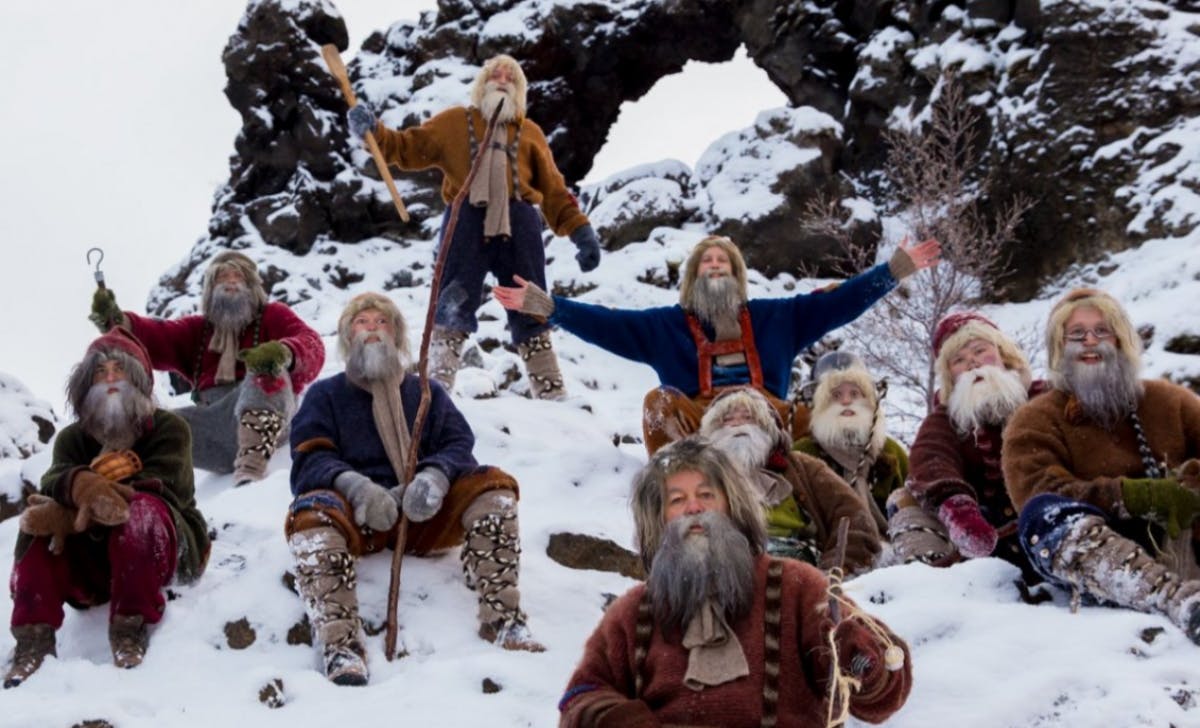 Ten of the 13 Yule Lads waving in a snow covered lava field
