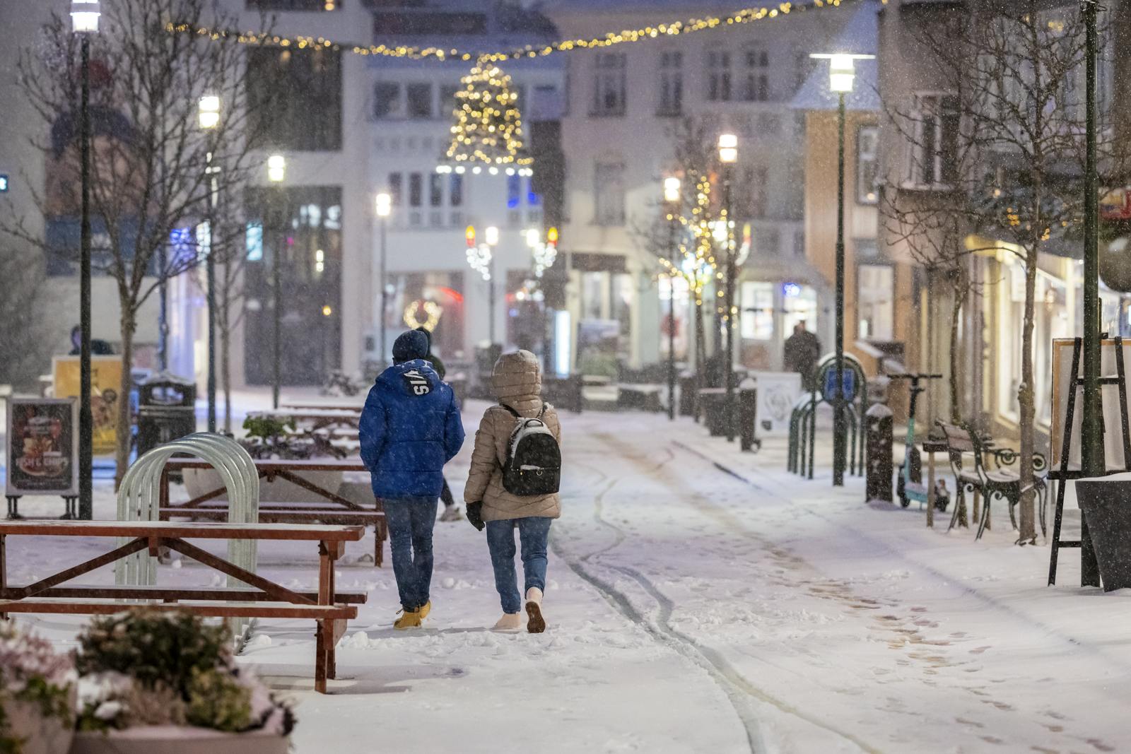 Two people walking down a snow covered shopping street