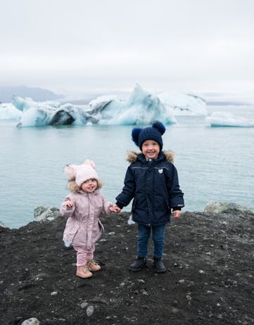 Two children standing in front of an icy lake