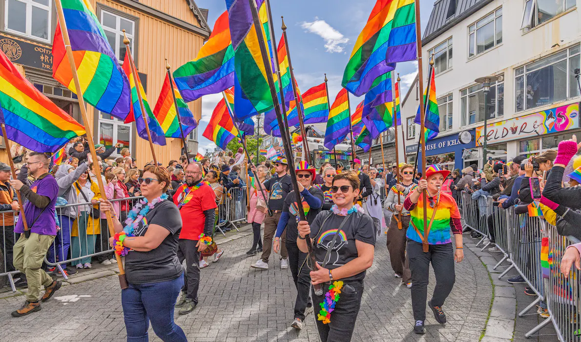 People parading down Laugavegur street in Icealand holding tainbow flags
