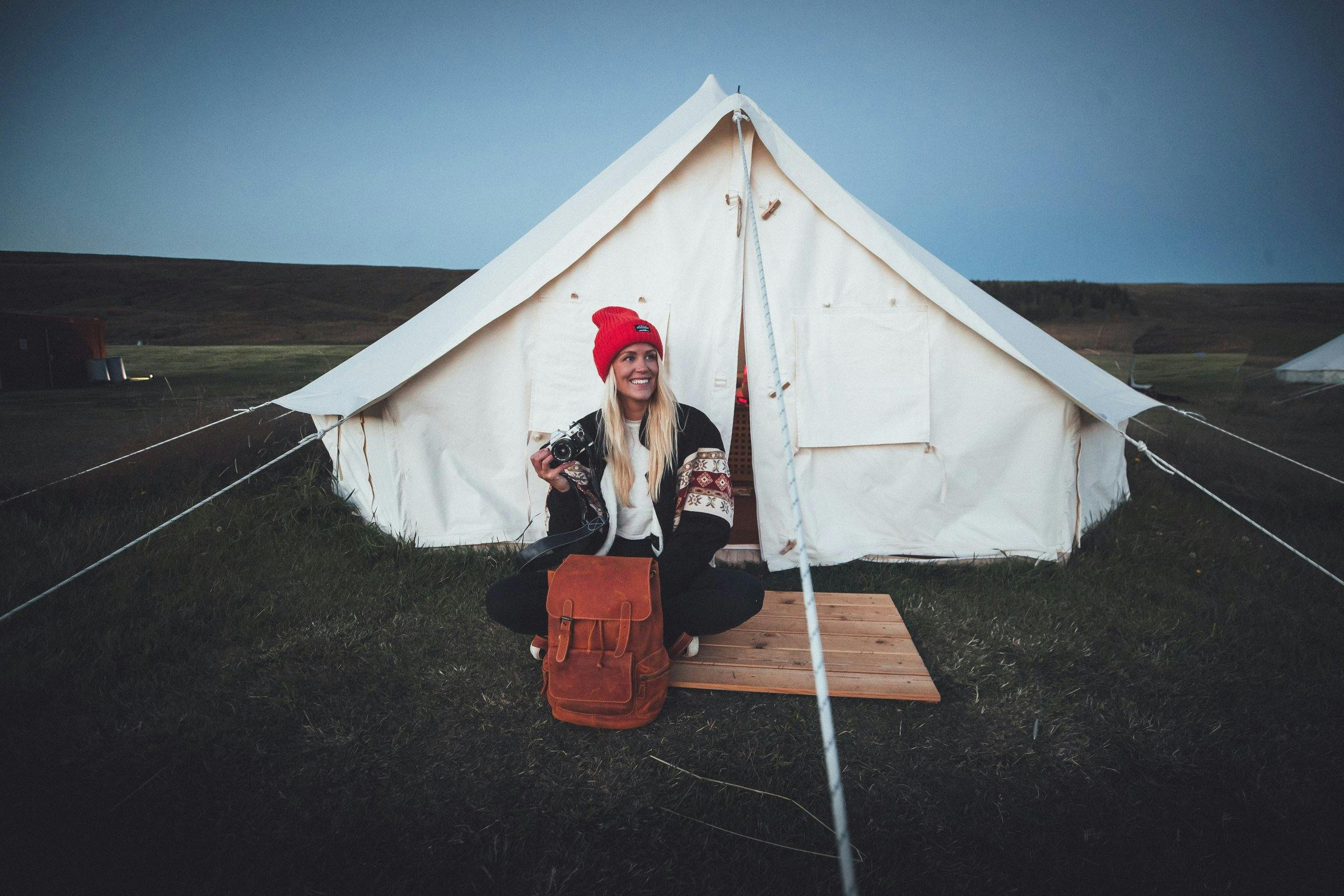 Young woman sitting in front of large white tent