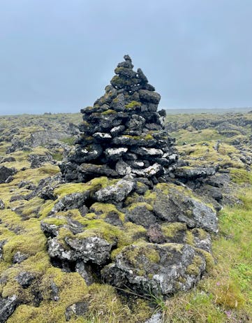 A mossy grown cairn made of black lava stones