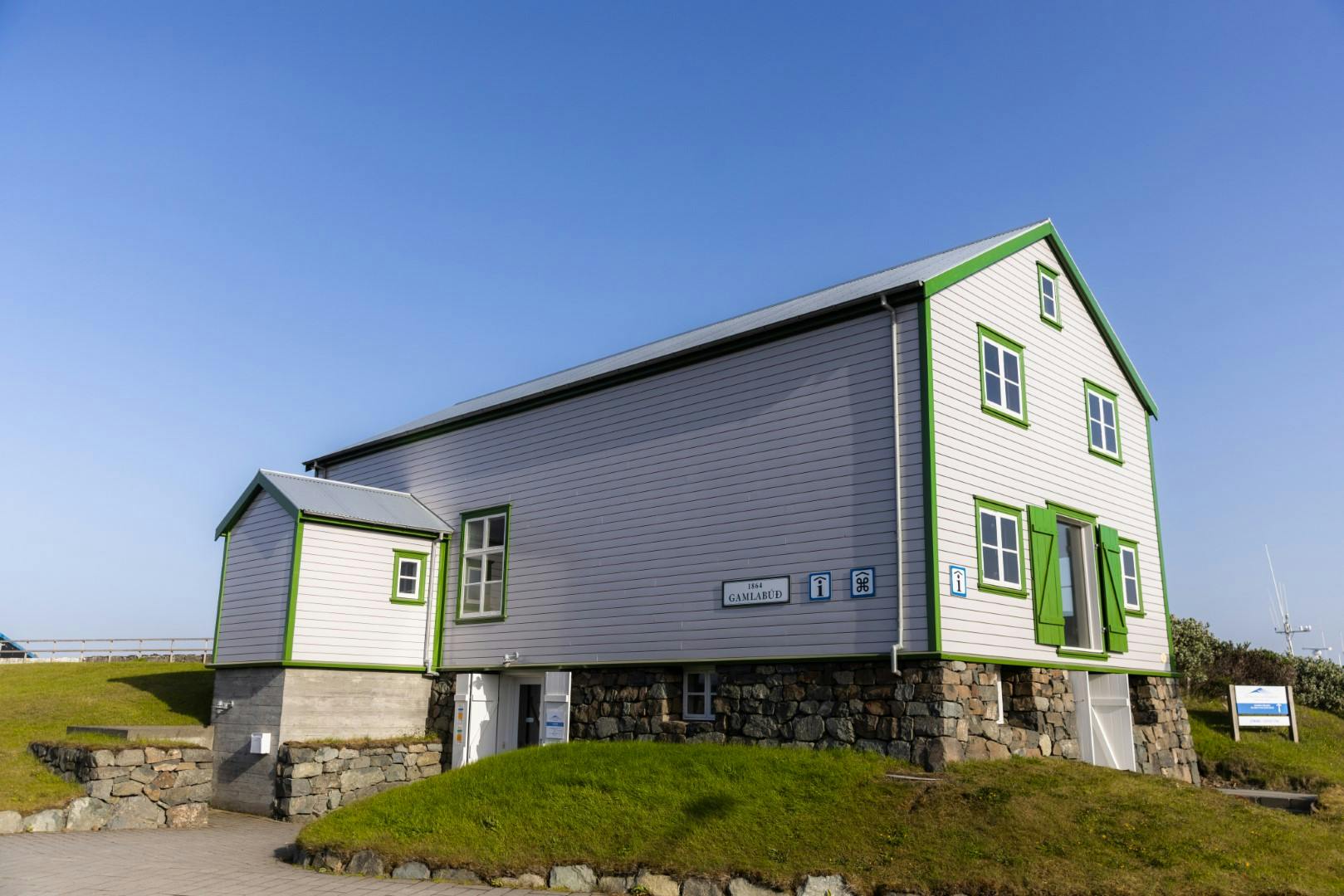 An old style wooden building on rock foundation, painted white with green dorrs and windows