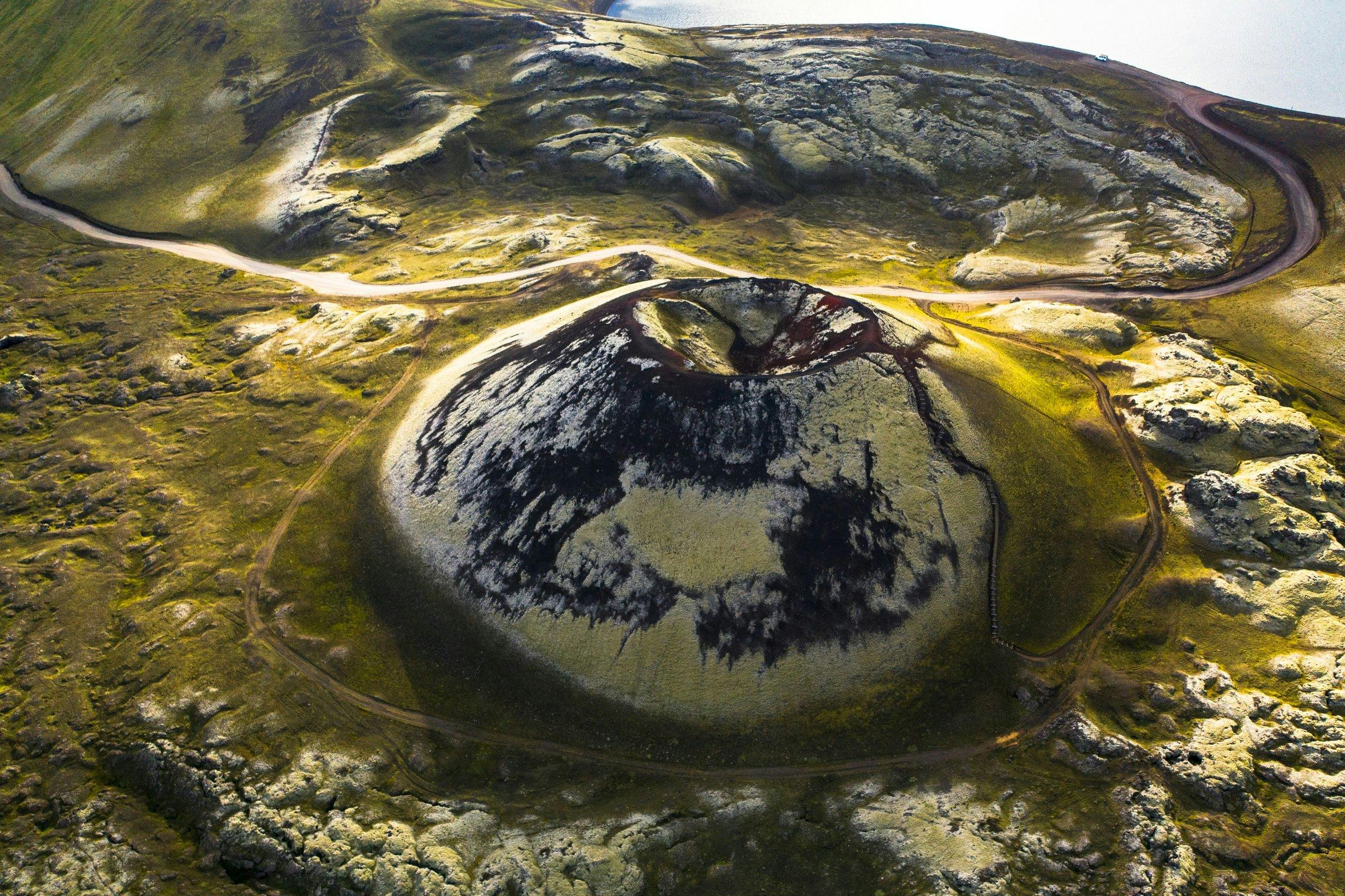 Aerial view of a volcanic crater surrounded by lava and moss