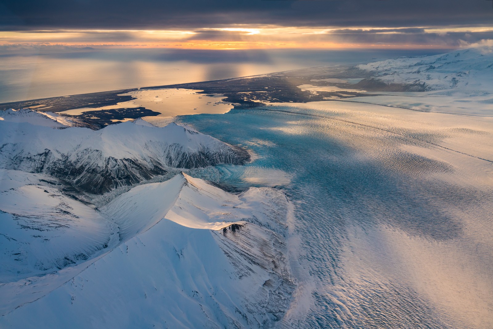 Aerial view of Vatnajökull glacier, with snow-covered peaks, glacial ice, and Iceland’s southeast coastline stretching toward the horizon.