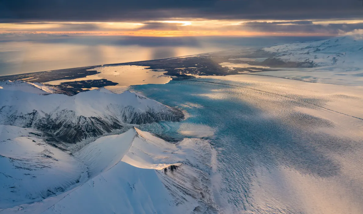 Aerial view of Vatnajökull glacier, with snow-covered peaks, glacial ice, and Iceland’s southeast coastline stretching toward the horizon.