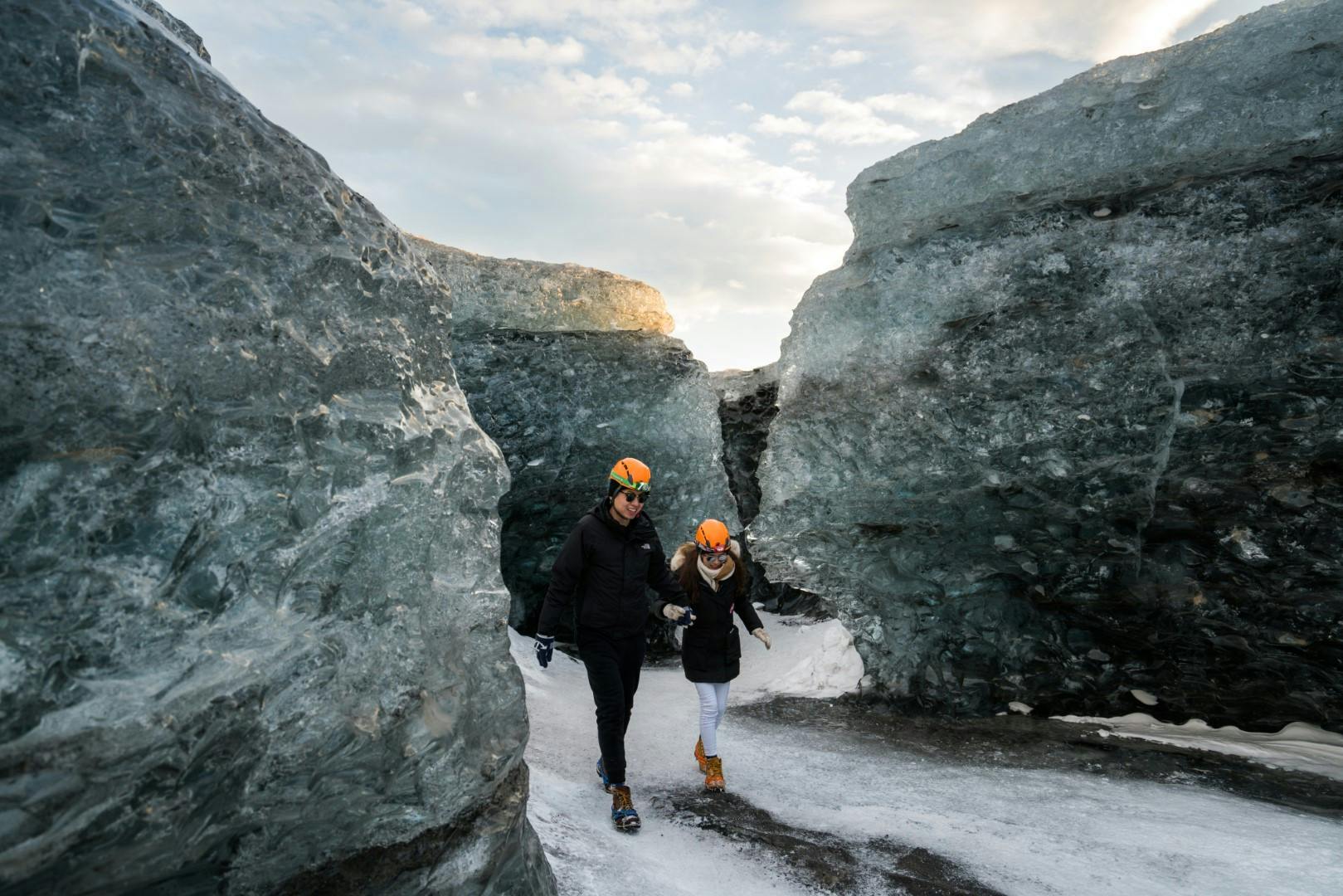 Couple walking between ice on a glacier
