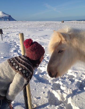 A woman talking to a horse in the snow