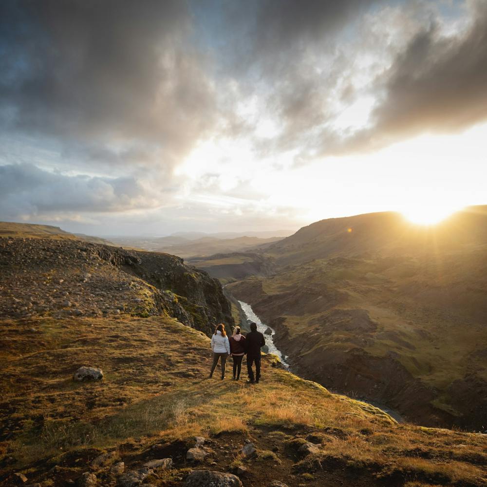 Three people watching the sunset at Háifoss