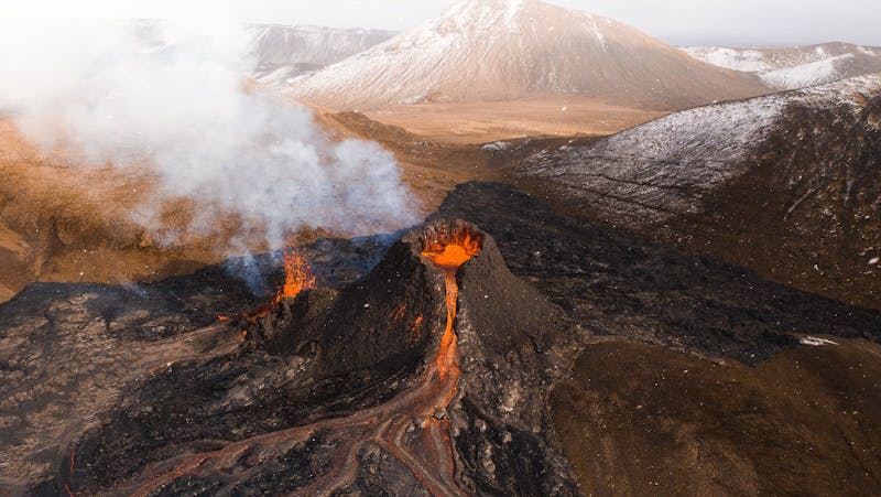 Two erupting craters with lava flowing from them in channels