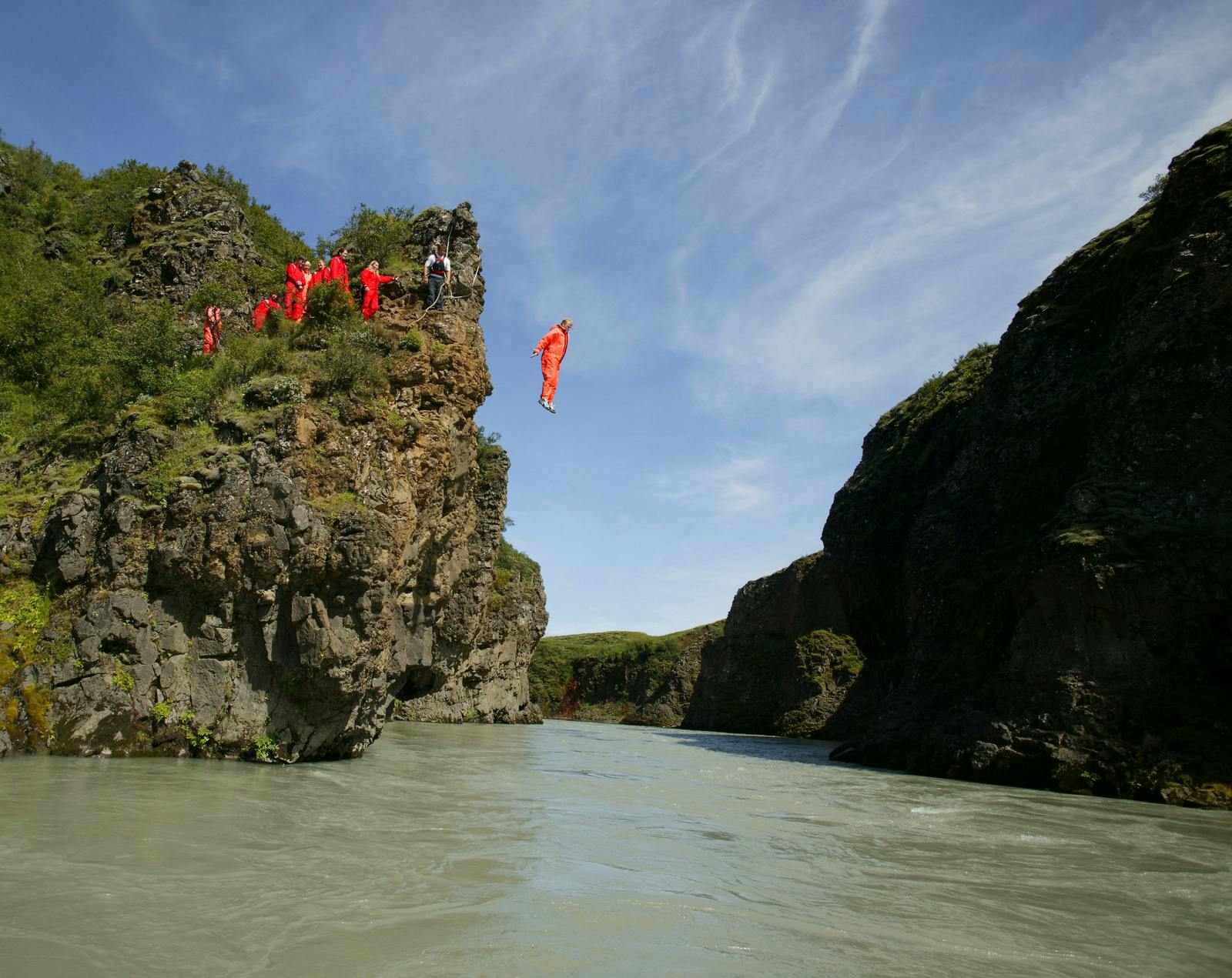 People jumping off a cliff into Icelandic glacial river