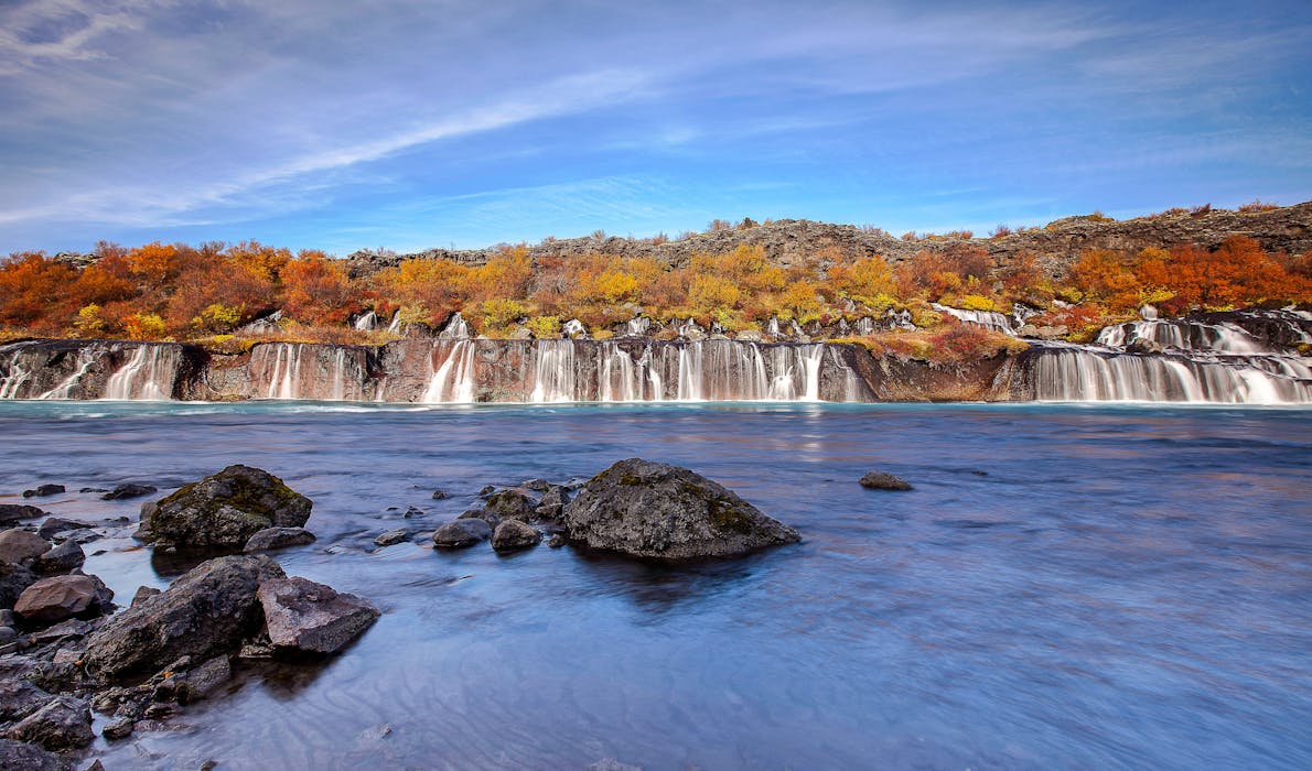 Hraunfossar Waterfalls flowing through lava fields surrounded by autumn colors in West Iceland, part of the Silver Circle route.