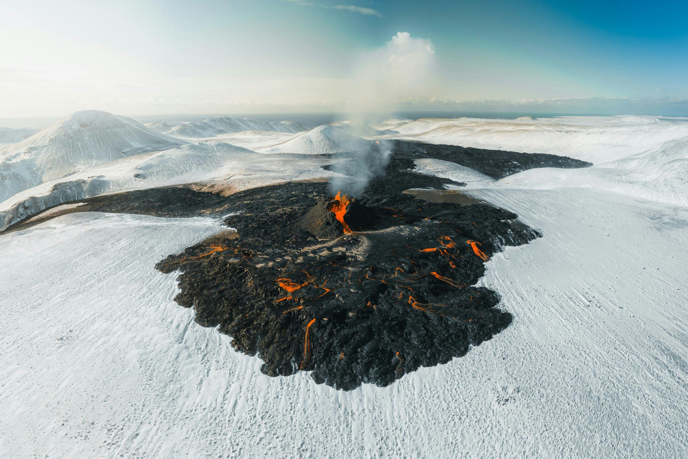 Erupting craters and a partly glowing black field flowing on a snowy surface