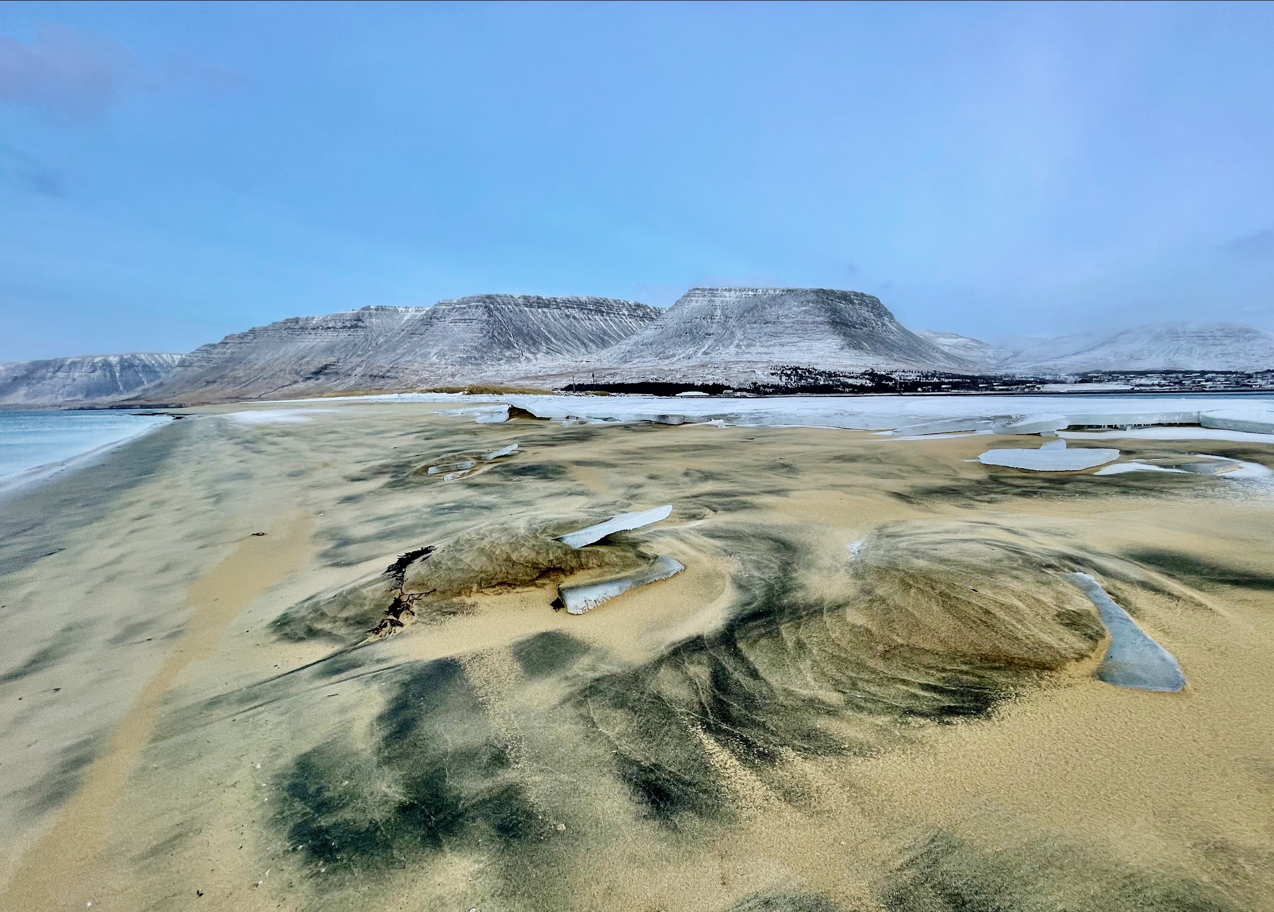 A golden-coloured beach with flat top mountains in the back