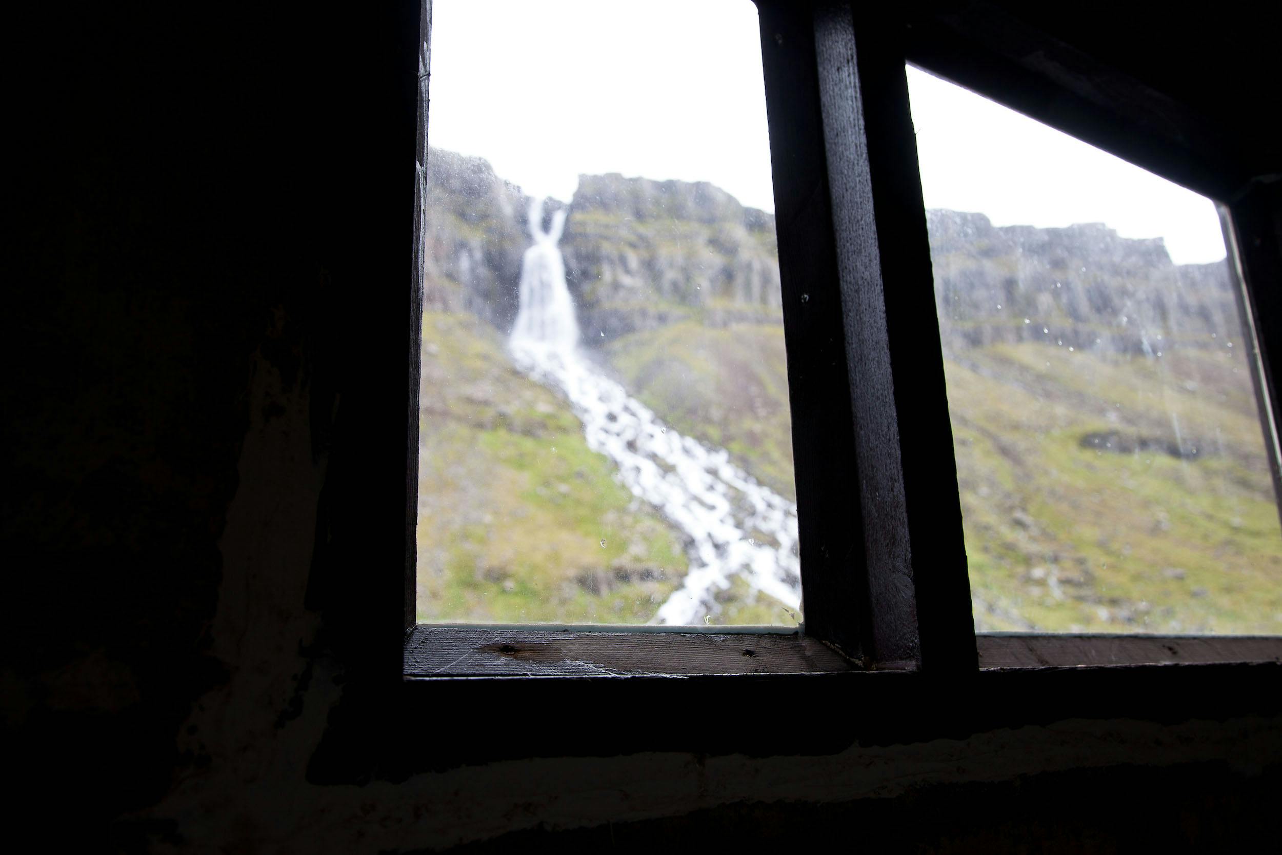 Waterfall visible through a window of the factory in Djúpavik