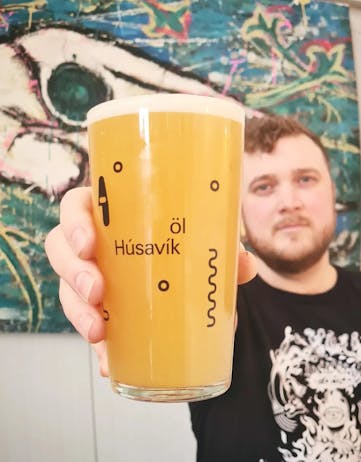 A man holding a larger glass of beer at Húsavík Öl brewery