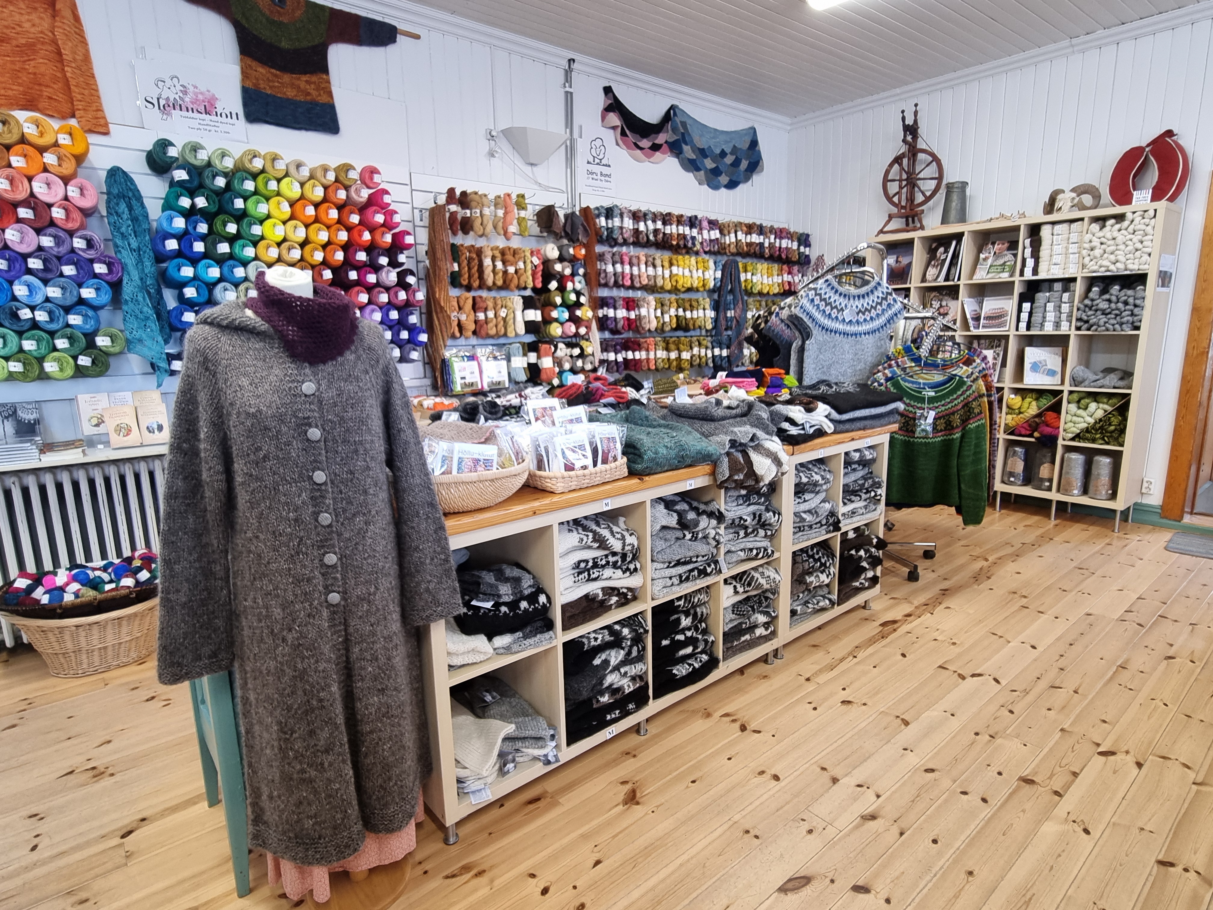 Interior of Þingborg Wool Store in Iceland, displaying shelves filled with colorful yarn, knitted sweaters, and handmade wool products crafted by local artisans.