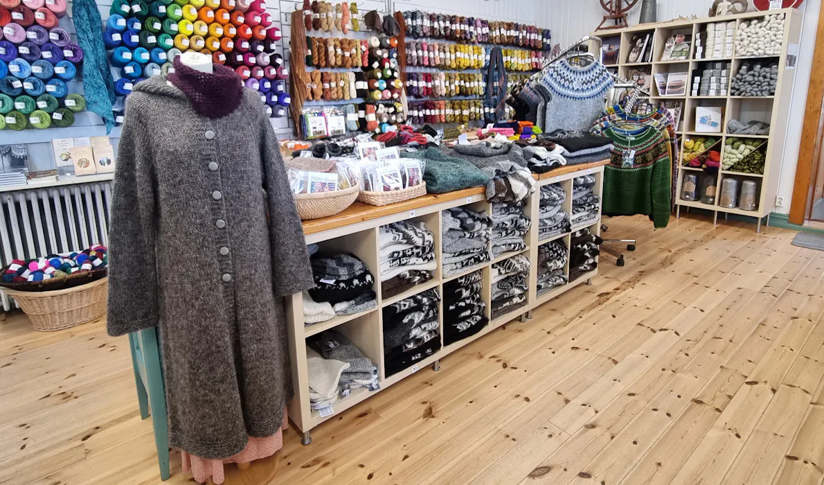 Interior of Þingborg Wool Store in Iceland, displaying shelves filled with colorful yarn, knitted sweaters, and handmade wool products crafted by local artisans.