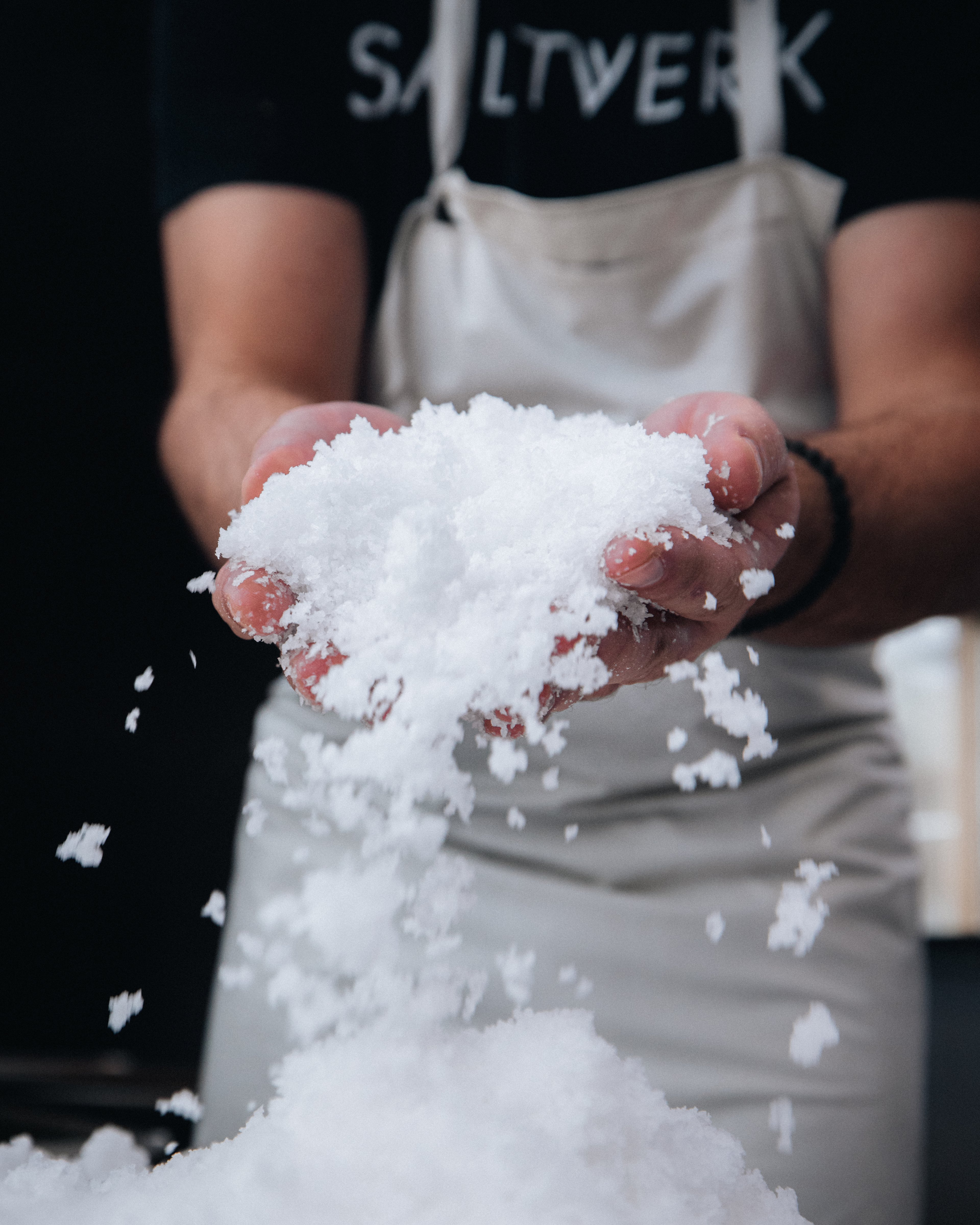 Hands holding freshly harvested flaky sea salt by Saltverk, showing coarse white salt crystals produced using geothermal energy in Iceland.