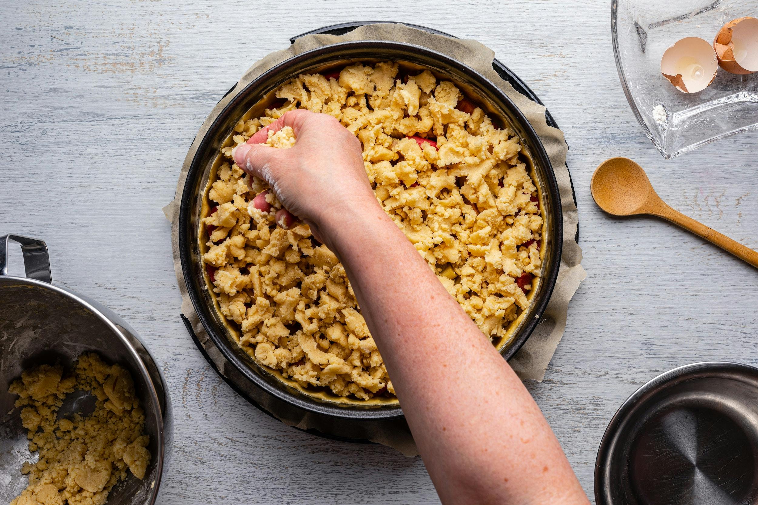 Baker putting crumbles on a cake