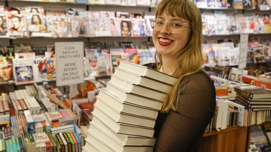 A bookseller at Eymundsson, a landmark bookstore in Reykjavík, carrying a best-seller. 