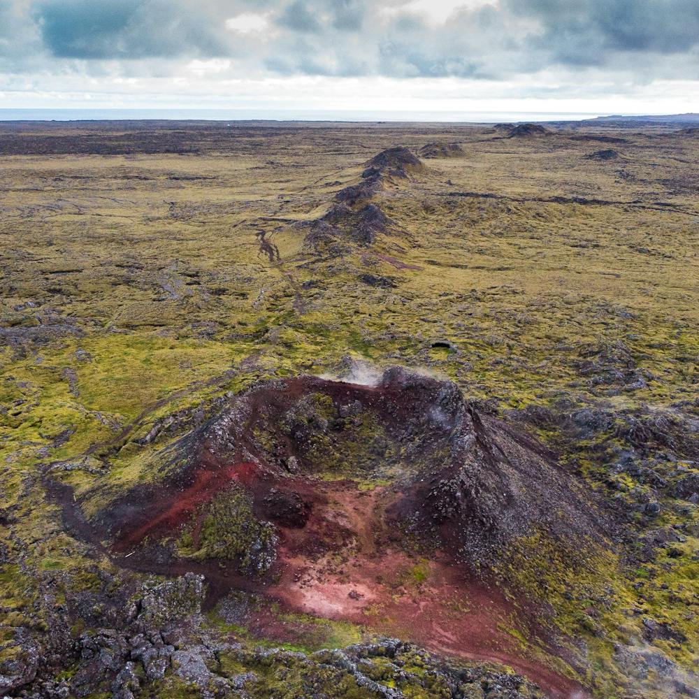 A series of volcanic craters surrounded by a moss-grown lava field