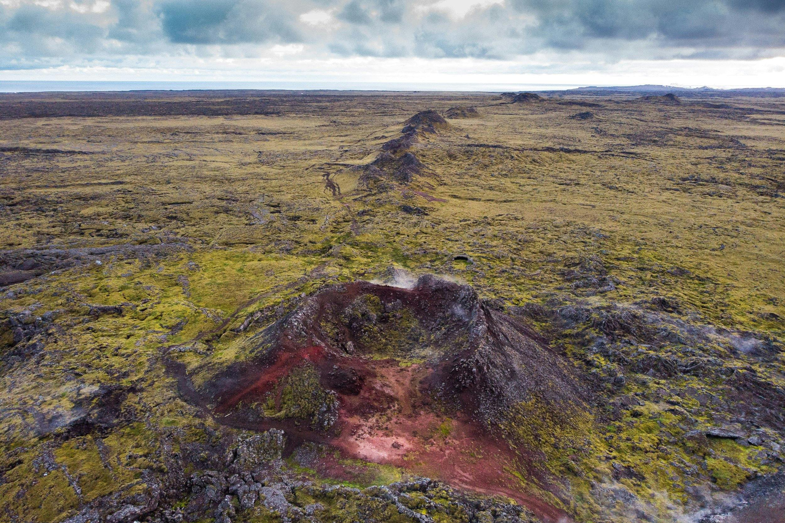 A series of volcanic craters surrounded by a moss-grown lava field