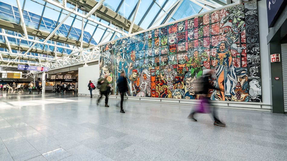 People inside Leifur Eiriksson airport terminal in front of colourful mural