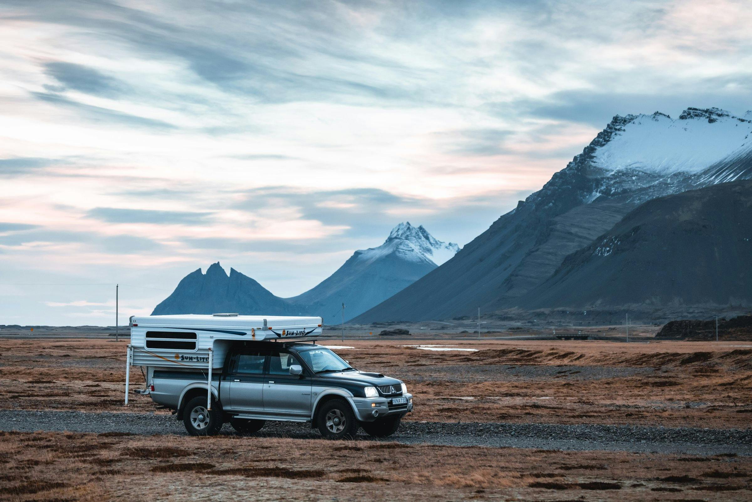 truck camper driving past snowy mountains in Iceland