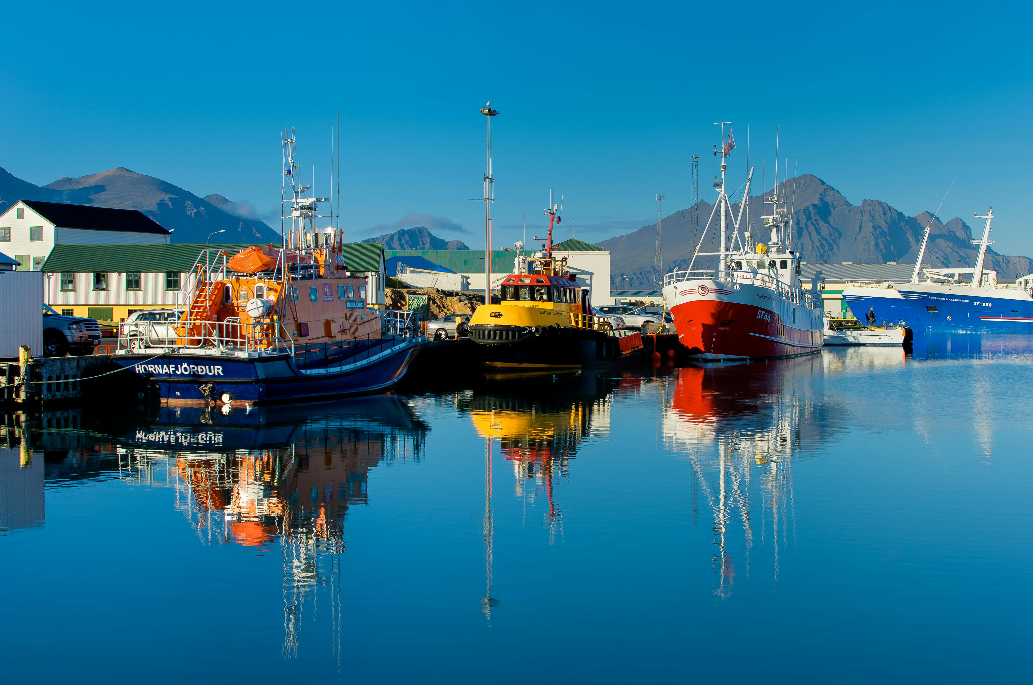 Colorful boats in a harbor reflecting in the calm sea