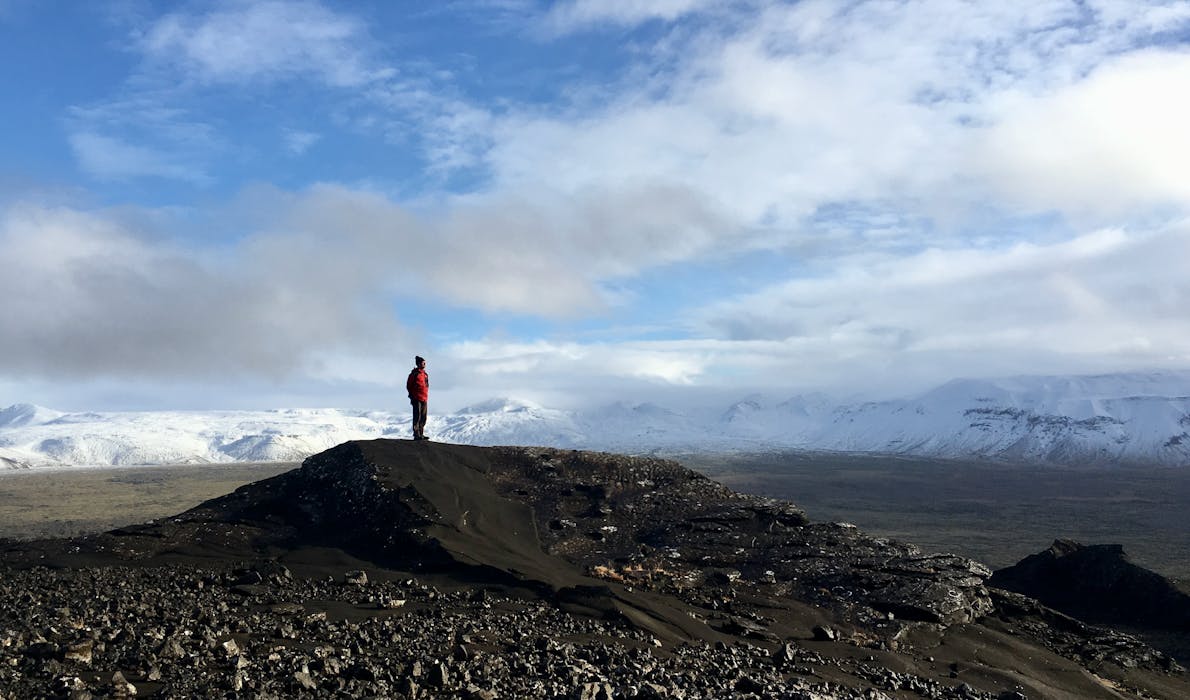 A man standing on top of a mountain admiring the surroundings