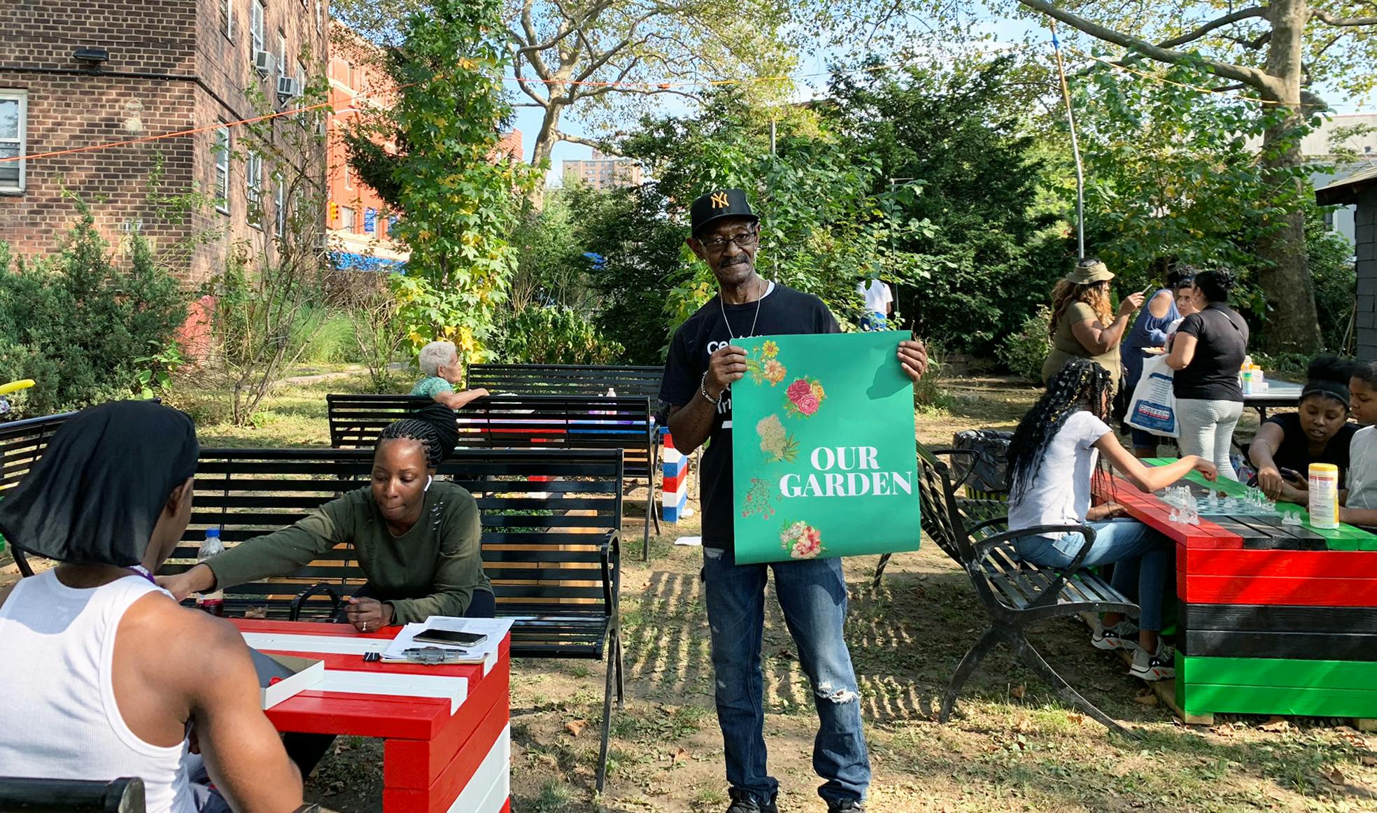 Eric Murray, long-time resident, community garden advocate and NeighborhoodStat founding member, holding up a mock-up of the garden sign during an event activating four community gardens and celebrating culture in 2019.