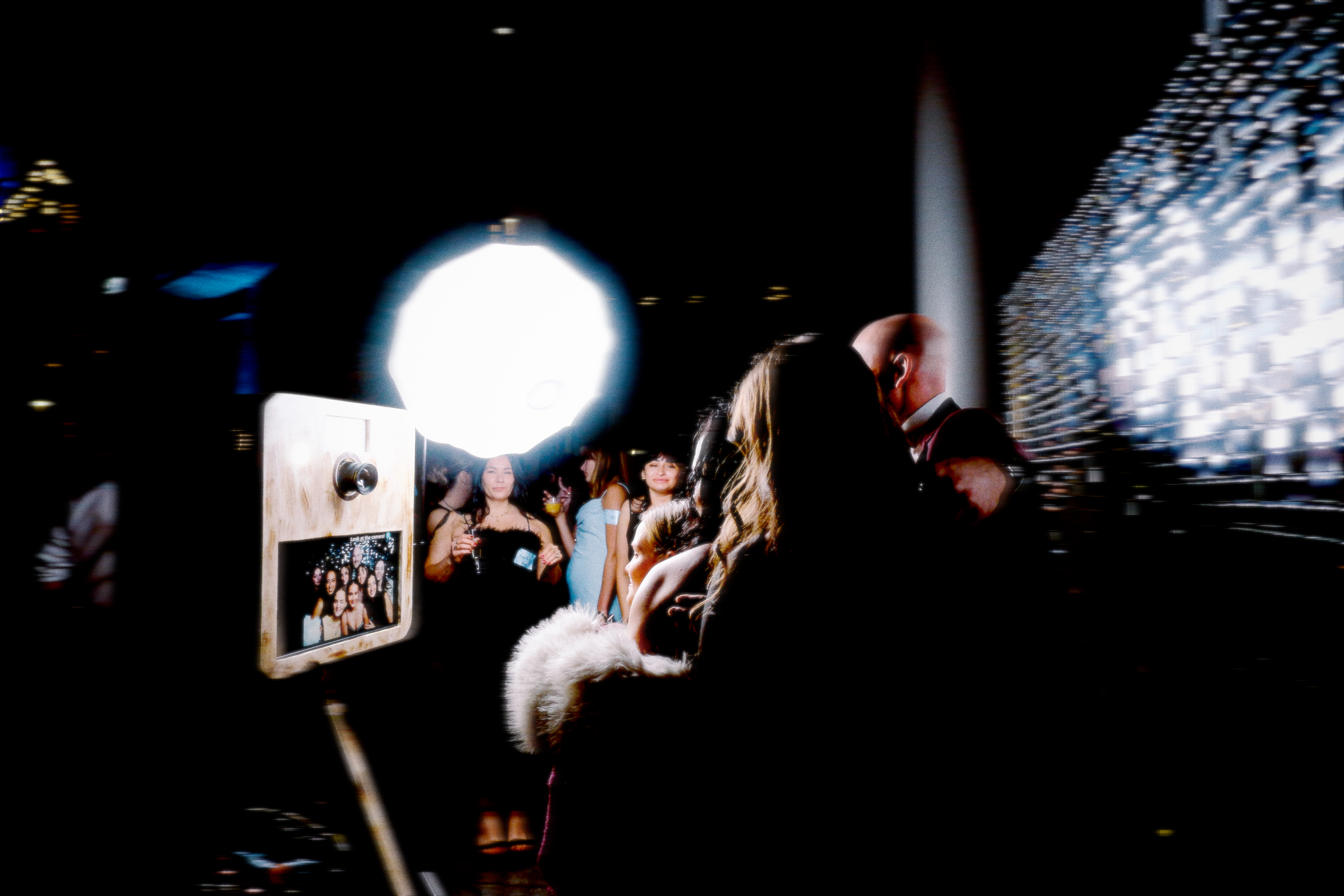 People posing in front of the photo booth with a Hollywood party atmosphere