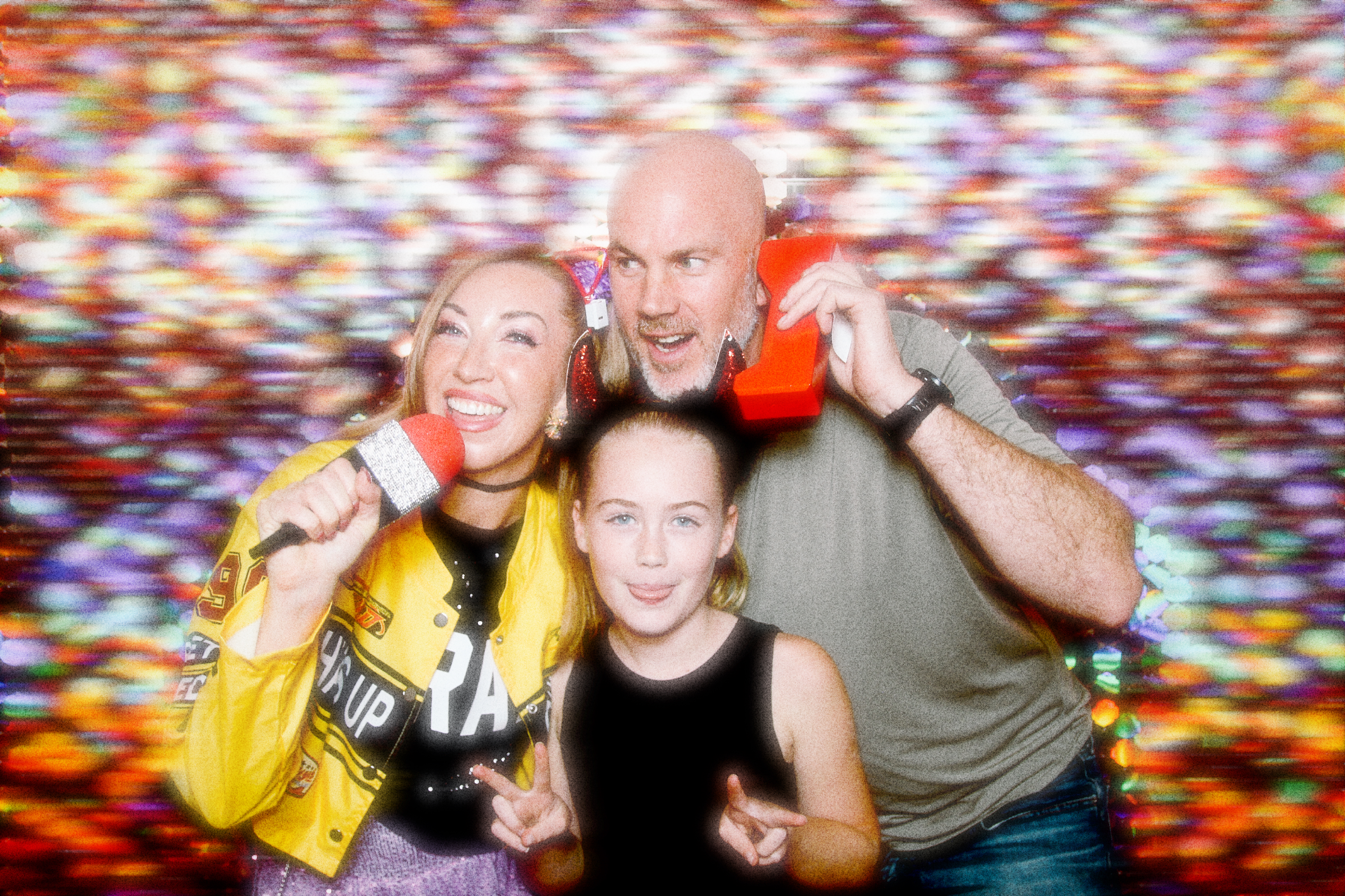 Two adults and a child having fun posing for a photo with props.