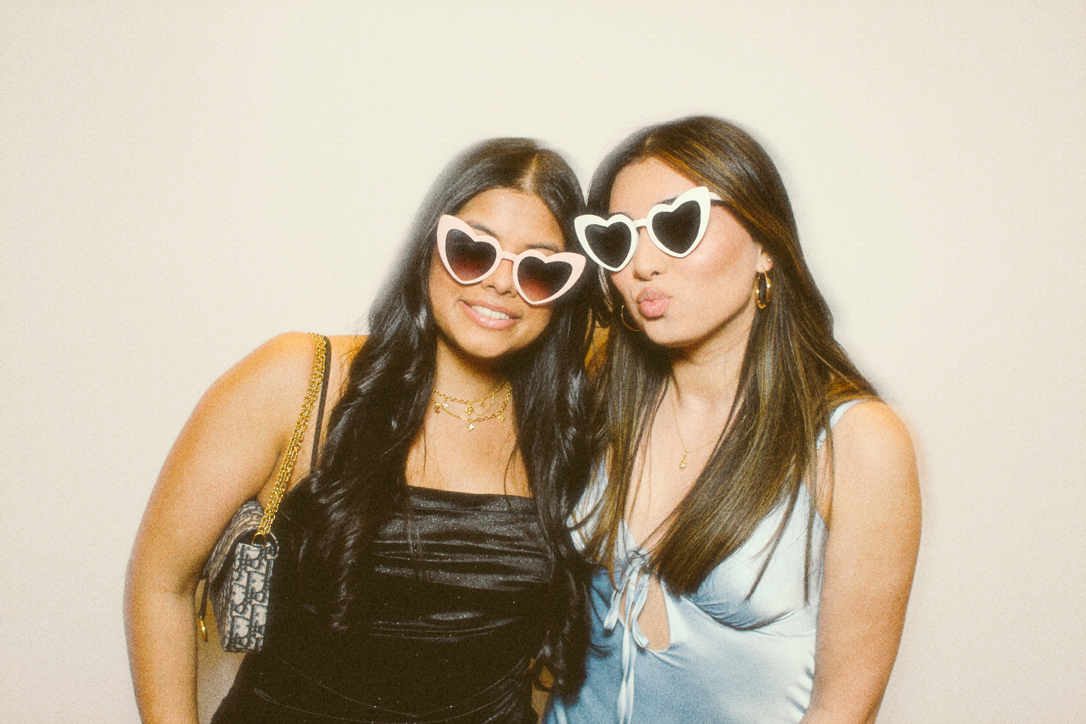 2 friends in pretty dresses posing in front of the photo booth 