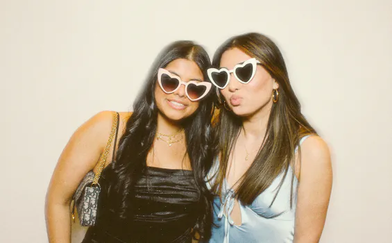 2 friends in pretty dresses posing in front of the photo booth