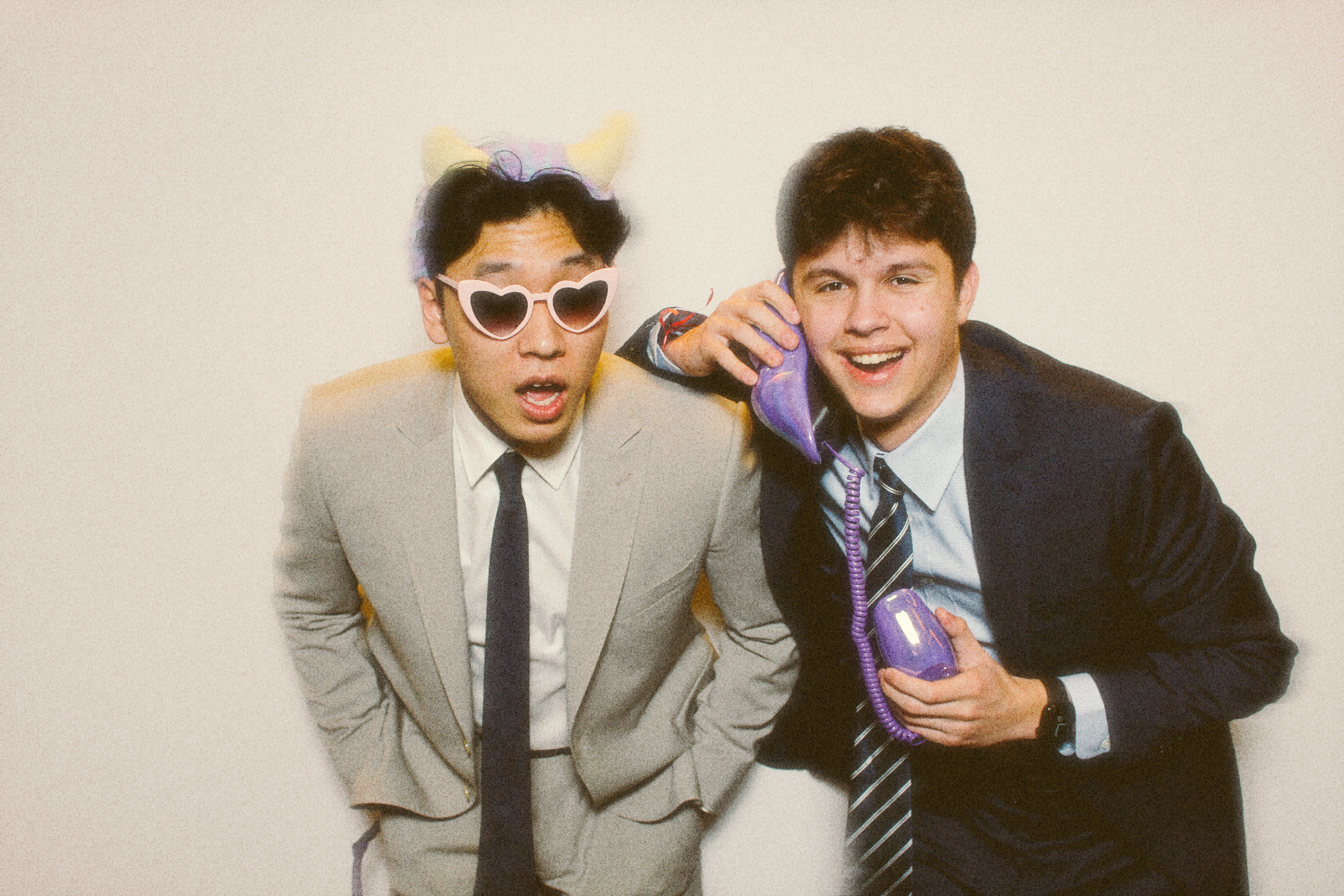 Two friends in suits with sunglasses pose for a photo.
