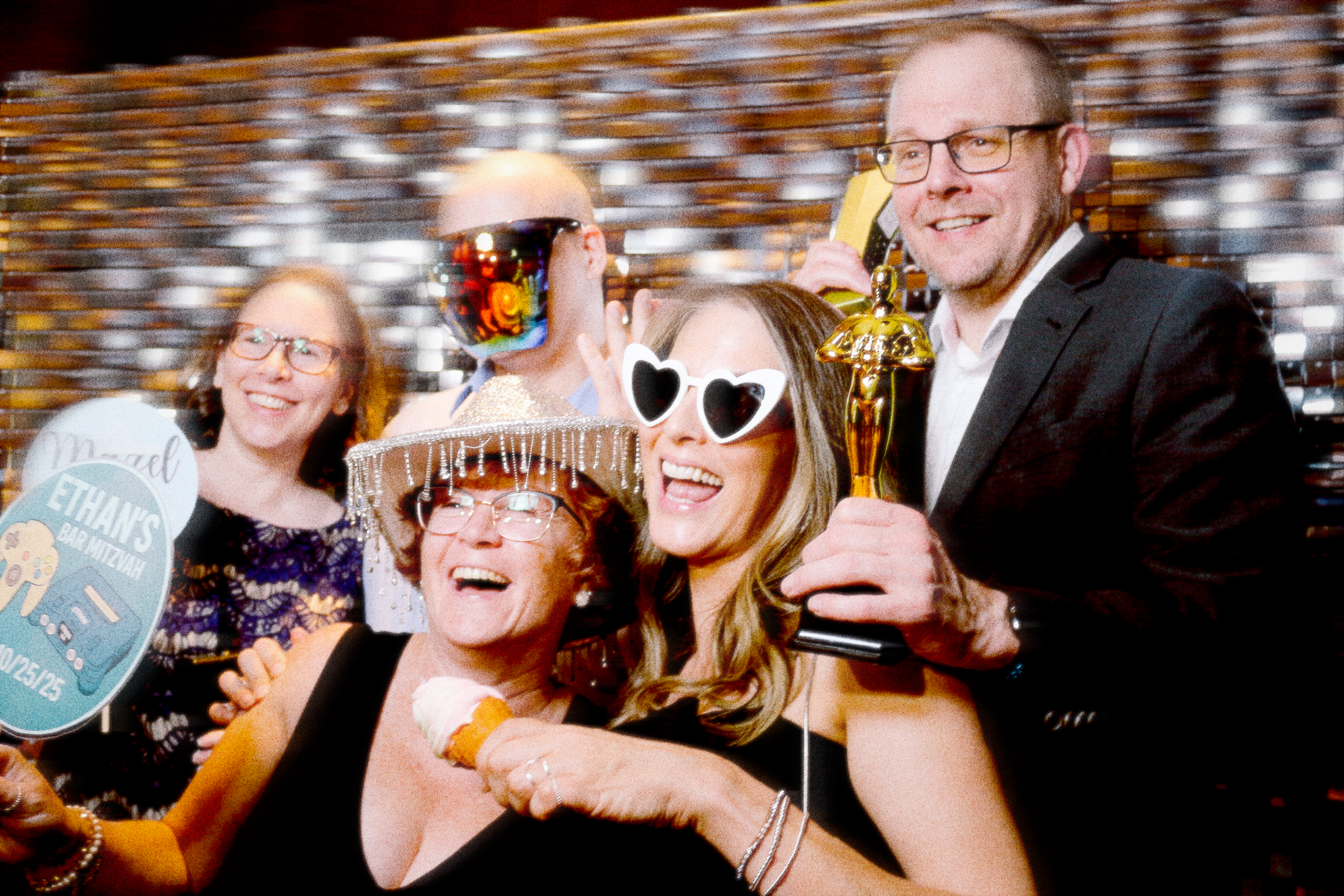 A group of friends and family posing in front of the photo booth for a private party