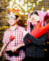 Two children in costume posing in front of the photo booth for a birthday party.