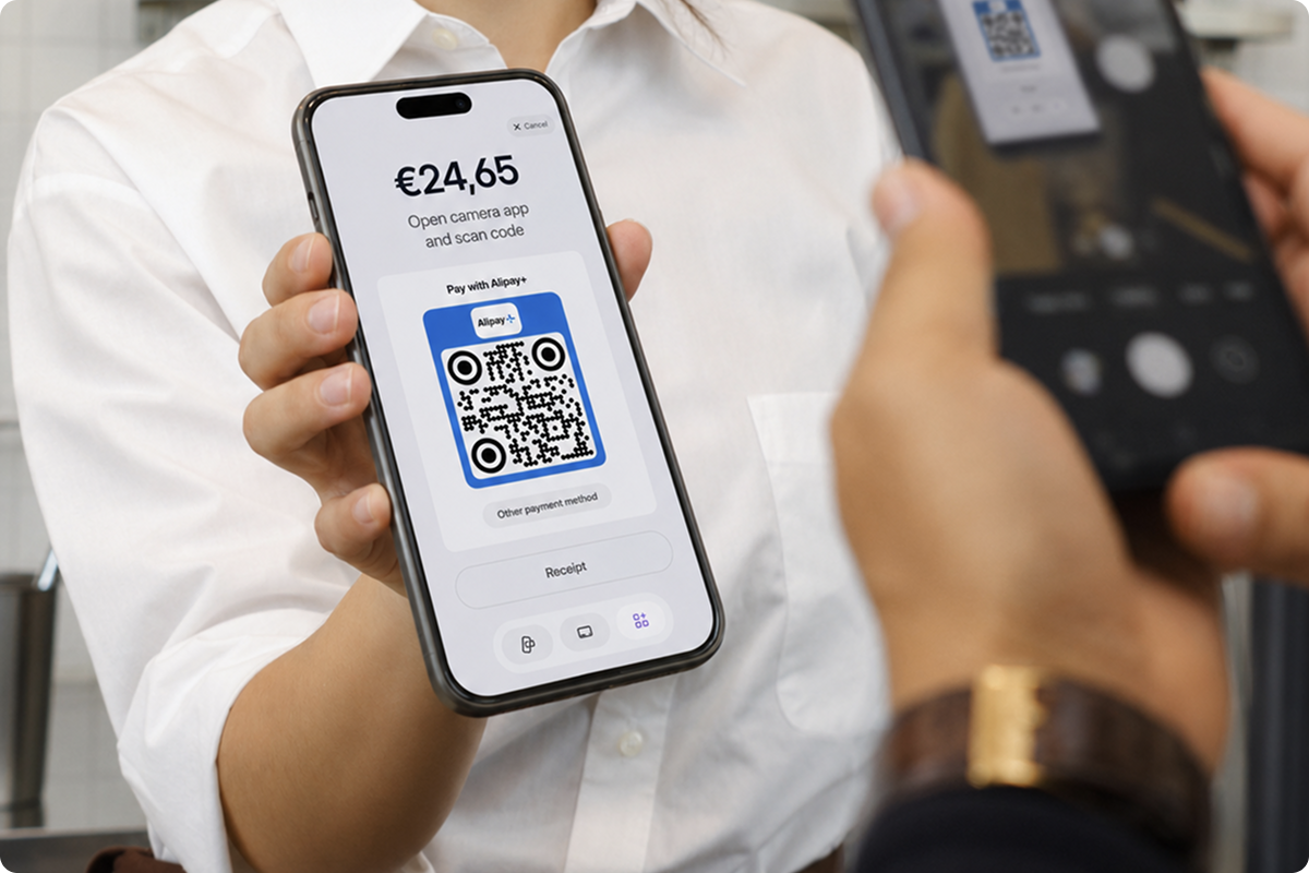 Pagamento tramite codice QR Alipay+ con viva.com — il commerciante mostra il codice QR Alipay+ sul proprio smartphone affinché il cliente possa scansionarlo e accetta pagamenti tramite portafogli digitali da parte di turisti asiatici.