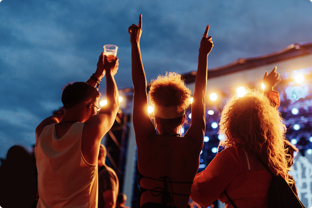 Soluções de pagamento para events e ticketing — multidão entusiasmada num festival com os braços erguidos sob as luzes do palco, pagamentos Viva.com sem falhas para events e experiências ao vivo