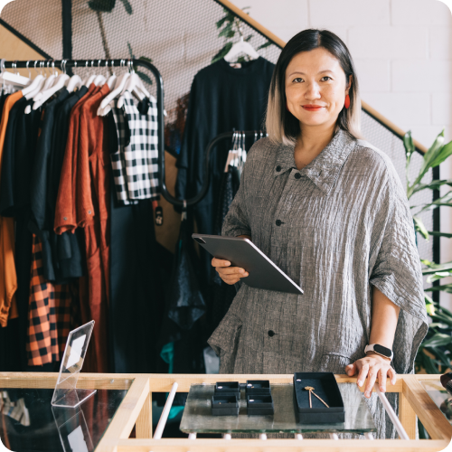 Boutique shop owner standing behind the counter with a tablet, ready to assist customers and manage digital payments.